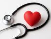 Stethoscope and red heart figurine arranged on a plain background