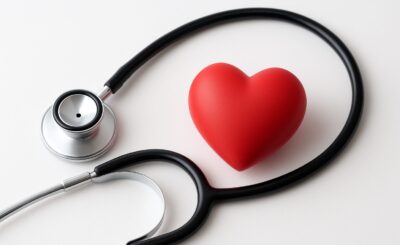 Stethoscope and red heart figurine arranged on a plain background