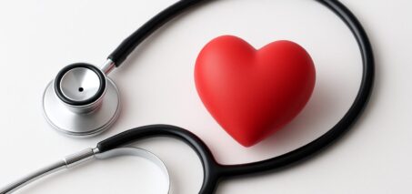 Stethoscope and red heart figurine arranged on a plain background