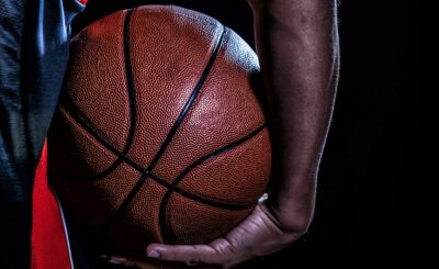 Close-up of a basketball held by a person's hand, with a dark background.