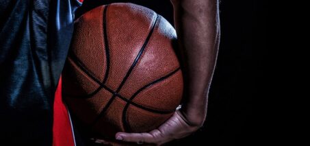 Close-up of a basketball held by a person's hand, with a dark background.